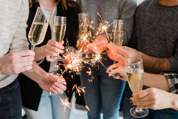 Group of friends holding flutes of sparkling champagne and burning bengal lights Group of happy friends holding flutes of sparkling champagne and burning bengal lights while enjoying party office parties stock pictures, royalty-free photos & images