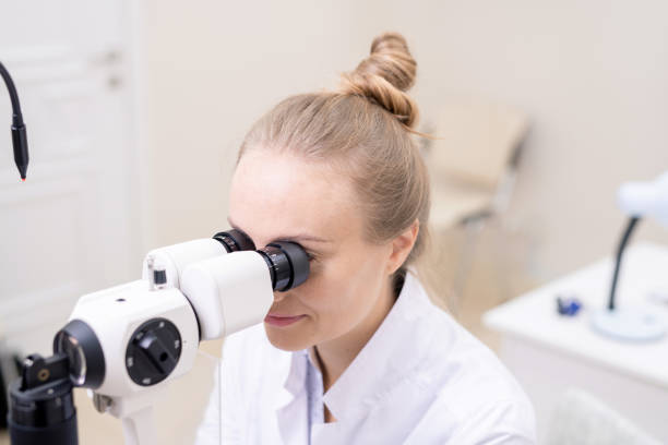 istock Young pretty eye doctor looking through optometric equipment 1180815588