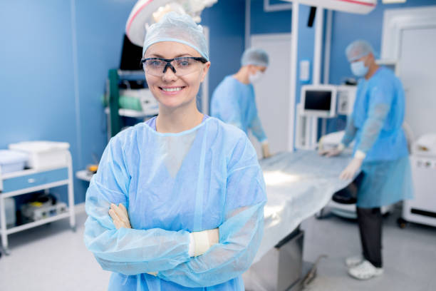 保護手袋と胸部によるユニフォーム横断腕の幸せな若いアシスタント - scrubs surgeon standing uniform ストックフォトと画像