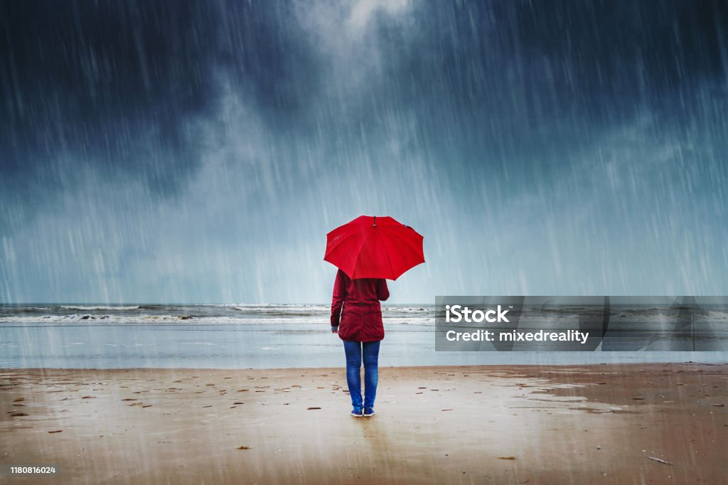 Woman in the rain Lonely woman with red umbrella is standing in the rain watching the sea Rain Stock Photo