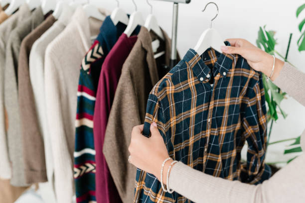 istock Young female shopper holding hanger with checkered shirt while choosing clothes 1180825191
