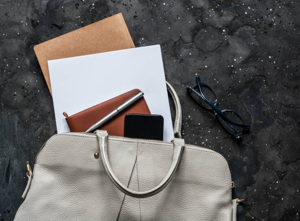 istock Women's bag with office accessories on a dark background, top view. Copy space 1180826868