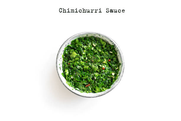 Chimichurri Sauce Raw homemade chopped green Chimichurri or Chimmichurri sauce made of parsley, garlic, oregano, hot pepper, olive oil, vinegar, isolated on white, top view, copy space. chimichurri stock pictures, royalty-free photos & images