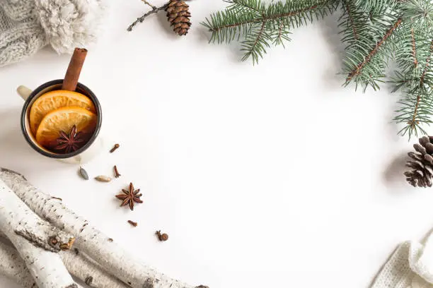 Winter seasonal concept. Christmas fir branches, pine cones,  knitted hat and hot drink isolated on white background. Trendy flat lay, top view, copy space.