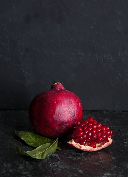 Ripe pomegranates on table against dark background. Space for text