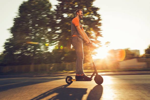 istock Hipster riding a scooter against sunset 1180832365
