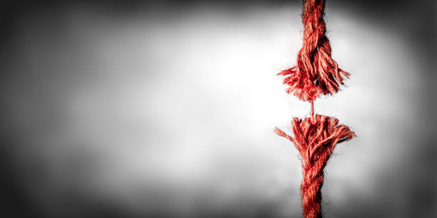 frayed red rope hanging by last thread - rope frayed emotional stress breaking photos et images de collection