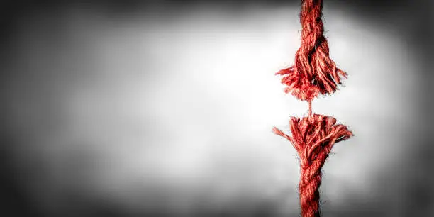 Frayed Red Rope Hanging By Last Thread On Black And White Background With Copy space
