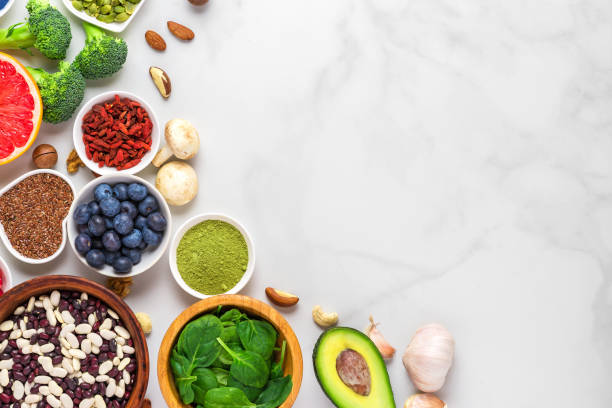selezione di cibo vegano sano: frutta, verdura, semi, superfood, noci, bacche su sfondo marmo bianco - superfood avocado fruit vegetable foto e immagini stock