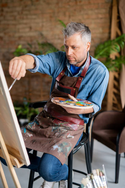 istock Concentrated professional painter with palette working over new painting 1180833744
