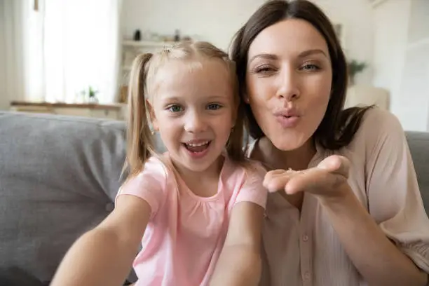 Photo of Head shot daughter and mother taking selfie, sending blow kiss