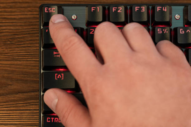 finger on keyboard presses escape male hand with index finger presses escape key on black keyboard with red backlight escape key escape computer push button stock pictures, royalty-free photos & images