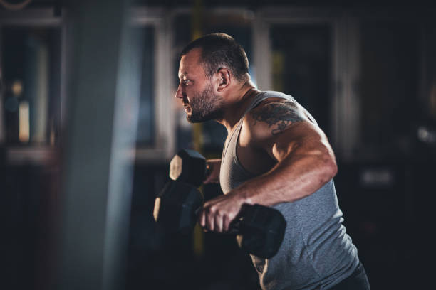 istock Muscular man doing exercises with dumbbells 1180836890