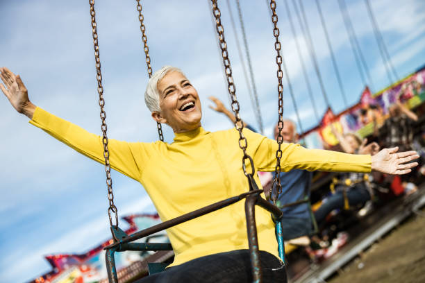 счастливая зрелая женщина весело провести время на цепи качели ездить в парке развлечений. - carnival amusement park swing traditional festival стоковые фото и изображения