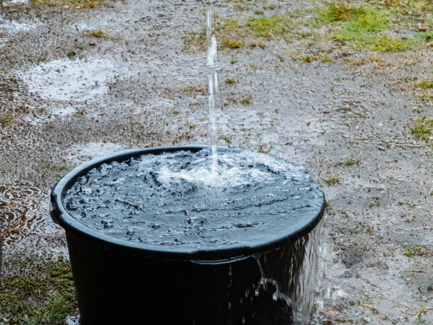 Water flowing from the height to the big black bucket. stock photo
