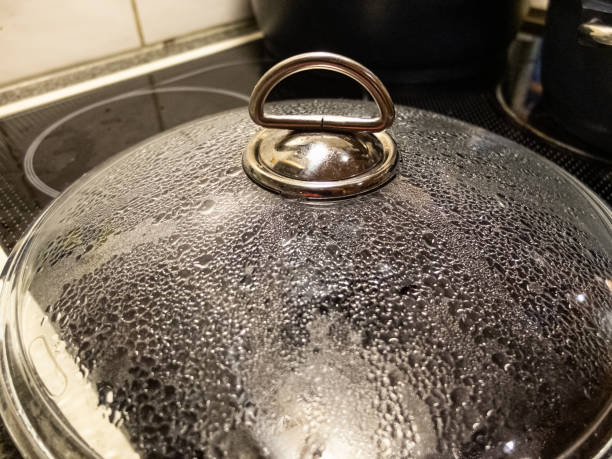 The pan lid on the kitchen covered by small water drops from inside. stock photo