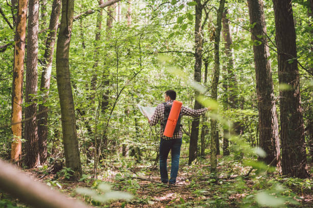 istock Man with Backpack and map searching directions in wilderness area. Tourist with backpack using map in forest. concept tourism holidays. Hiking man. Traveling man lost walking in forest looking at map 1180843030