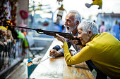 Senior couple having fun while shooting at target at amusement park.
