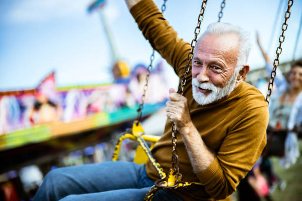 istock Happy mature man having fun on a chain swing ride at amusement park. 1180844113