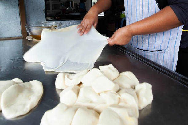 Close shot of woman hands kneading Roti dough with oil on the stainless-steel table. Close shot of woman hands kneading Roti dough with oil on the stainless-steel table. Motion blur. roti canai stock pictures, royalty-free photos & images