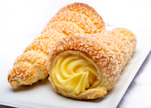 Filled with yellow cream homemade horn pastry close up