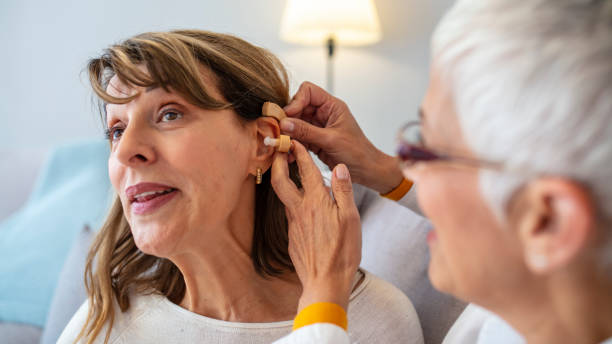 istock Senior woman adjusting hearing aid in doctor's office 1180852883