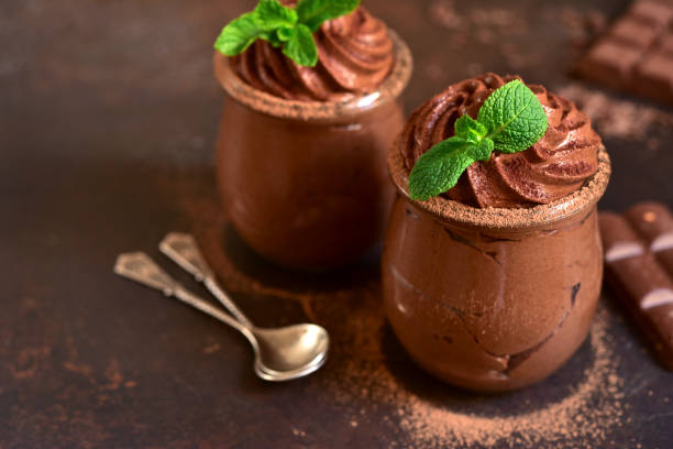 Homemade delicious chocolate mousse with mint Homemade delicious chocolate mousse with mint in a jars on a dark slate, stone or concrete background. parfait photos stock pictures, royalty-free photos & images