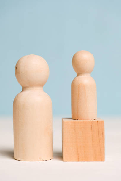 istock Wooden figures with a cube on a blue background. Mentoring concept. A professional teaches a student. Close up. 1180860464