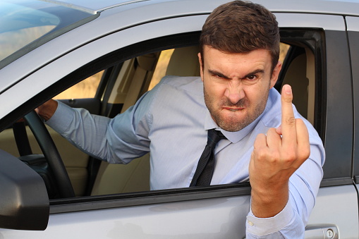 Angry businessman showing middle finger while driving.