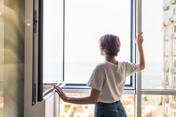 mujer joven abrir ventana en la mañana en casa - window sun sunlight vertical fotografías e imágenes de stock