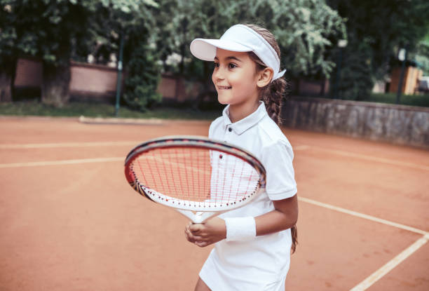 bella ragazza con racchetta in mano che gioca a tennis - tennis child teenager childhood foto e immagini stock