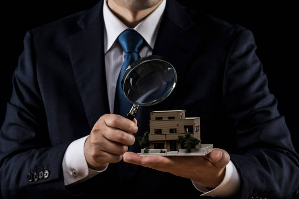 istock Businessman with house model and loupe 1180890118