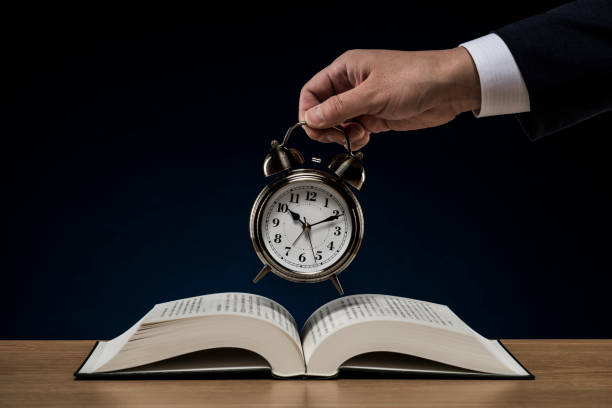 istock Businessman with open book and alarm clock 1180890829