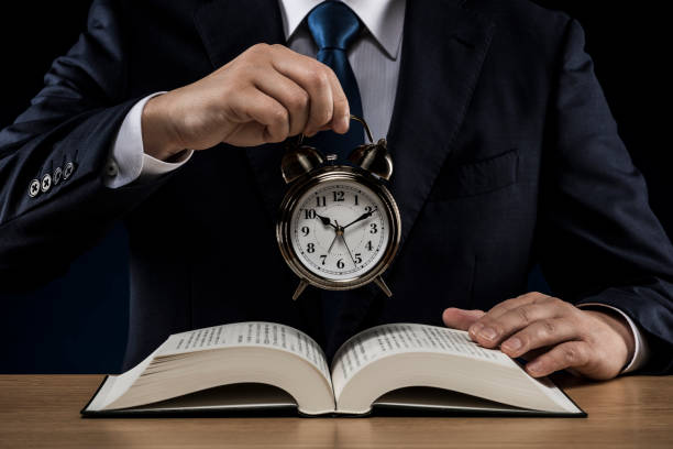 istock Businessman with open book and alarm clock 1180891006