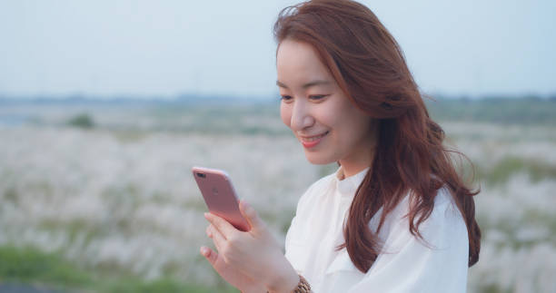istock Pretty Asian Girl Using Smart Phone In Park 1180894542