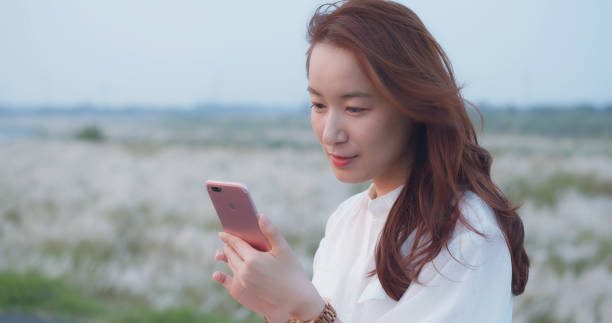 istock Pretty Asian Girl Using Smart Phone In Park 1180894620