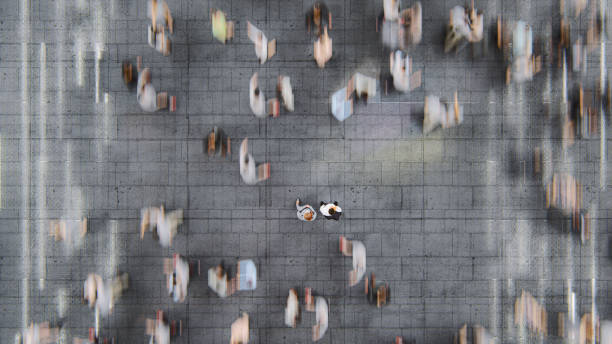 Businessman standing in the fast moving crowds of commuters Businessman standing in the fast moving crowds of commuters. This is entirely 3D generated image. looking down stock pictures, royalty-free photos & images