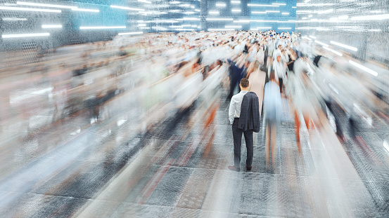 Businessman standing in the fast moving crowds of commuters. This is entirely 3D generated image.