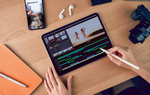 istock Concept of simple operation of blogger and vlogger, hand using digital pen on video editor works with footage on tablet, camera and accessories on table. 1180897631