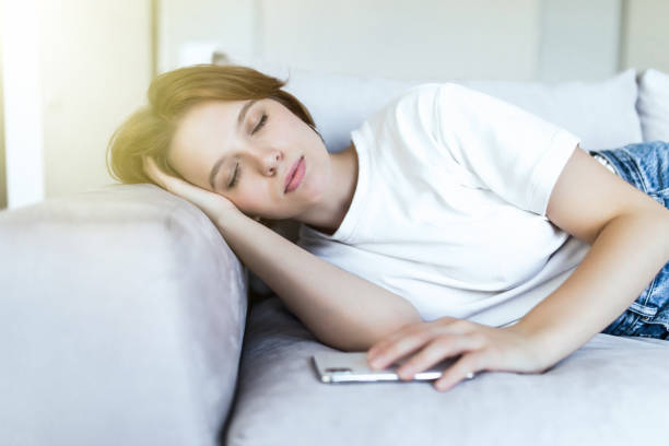 istock Beautiful young woman sleeping on sofa in lounge 1180898404