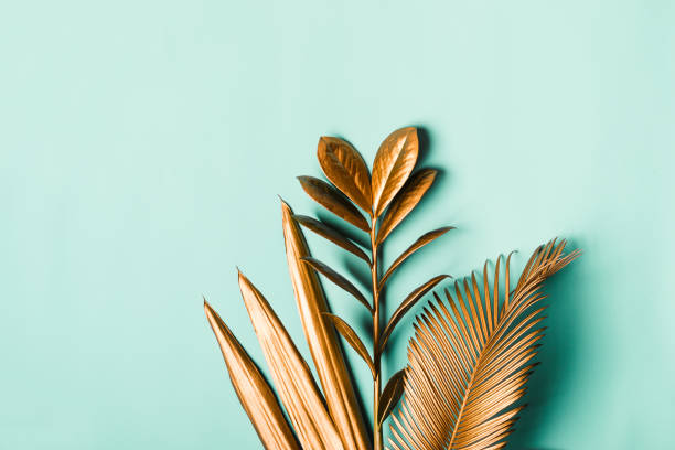 istock Tropical palm leaves painted with gold paint on delicate pastel mint background 1180898920