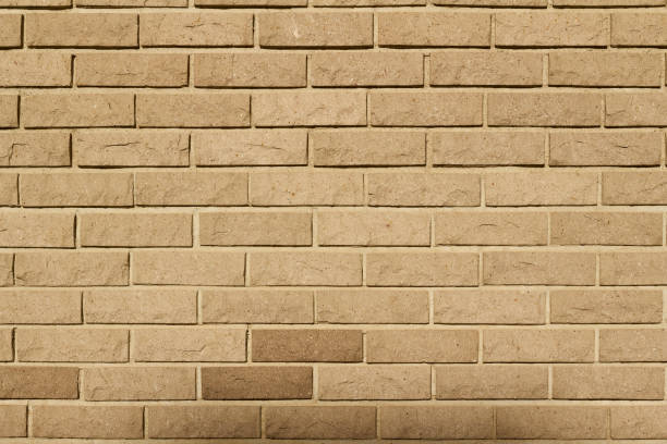 istock Rounded rough textured natural stone brick wall background in a tan color 1180899592
