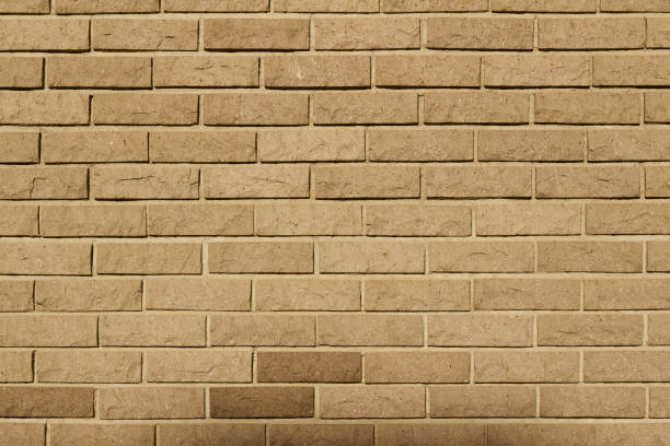 Rounded rough textured natural stone brick wall background in a tan color