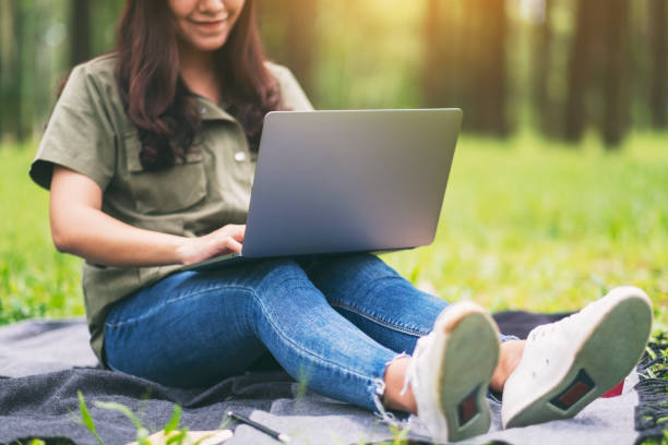 istock woman working and typing on laptop keyboard while sitting in the park 1180900303
