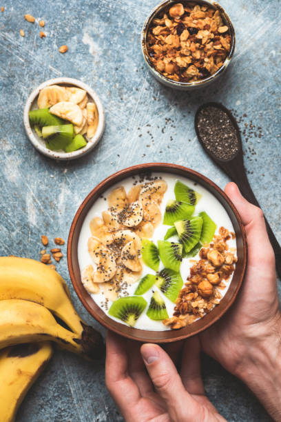 istock Hands holding smoothie bowl with fruits and granola 1180901330