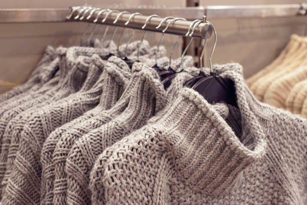 istock Gray sweaters hanging on hangers in store women's clothing 1180904209