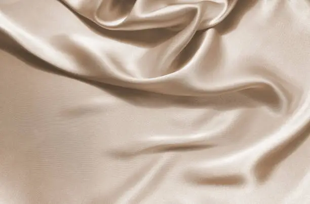 Photo of Delicate satin draped fabric beige texture for festive backgrounds