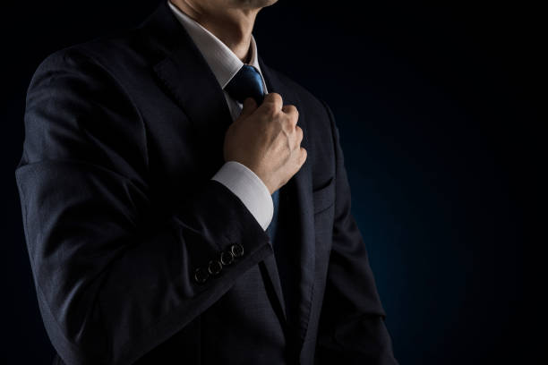 istock Businessman tightens tie. Over black background. 1180905414