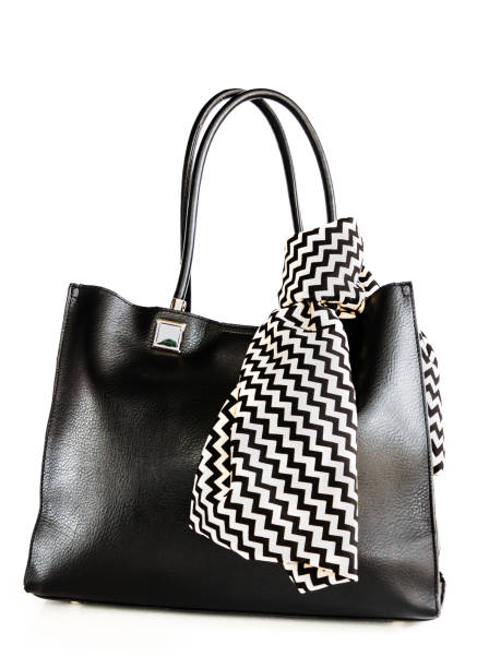 istock Black leather female bag and a scarf with geometric pattern tied to a handle isolated on white background. Closeup 1180908486