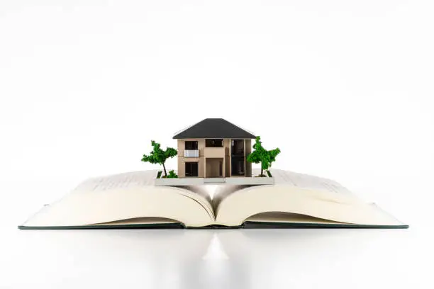 Open book and architectural model on a white background.